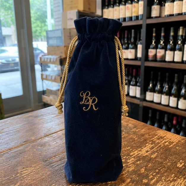 Custom velvet drawstring wine bag with a satin cord and gold embroidered logo for a luxury bottle